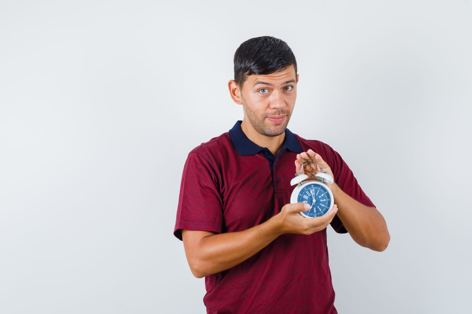 young-man-holding-alarm-clock-t-shirt-looking-positive-front-view